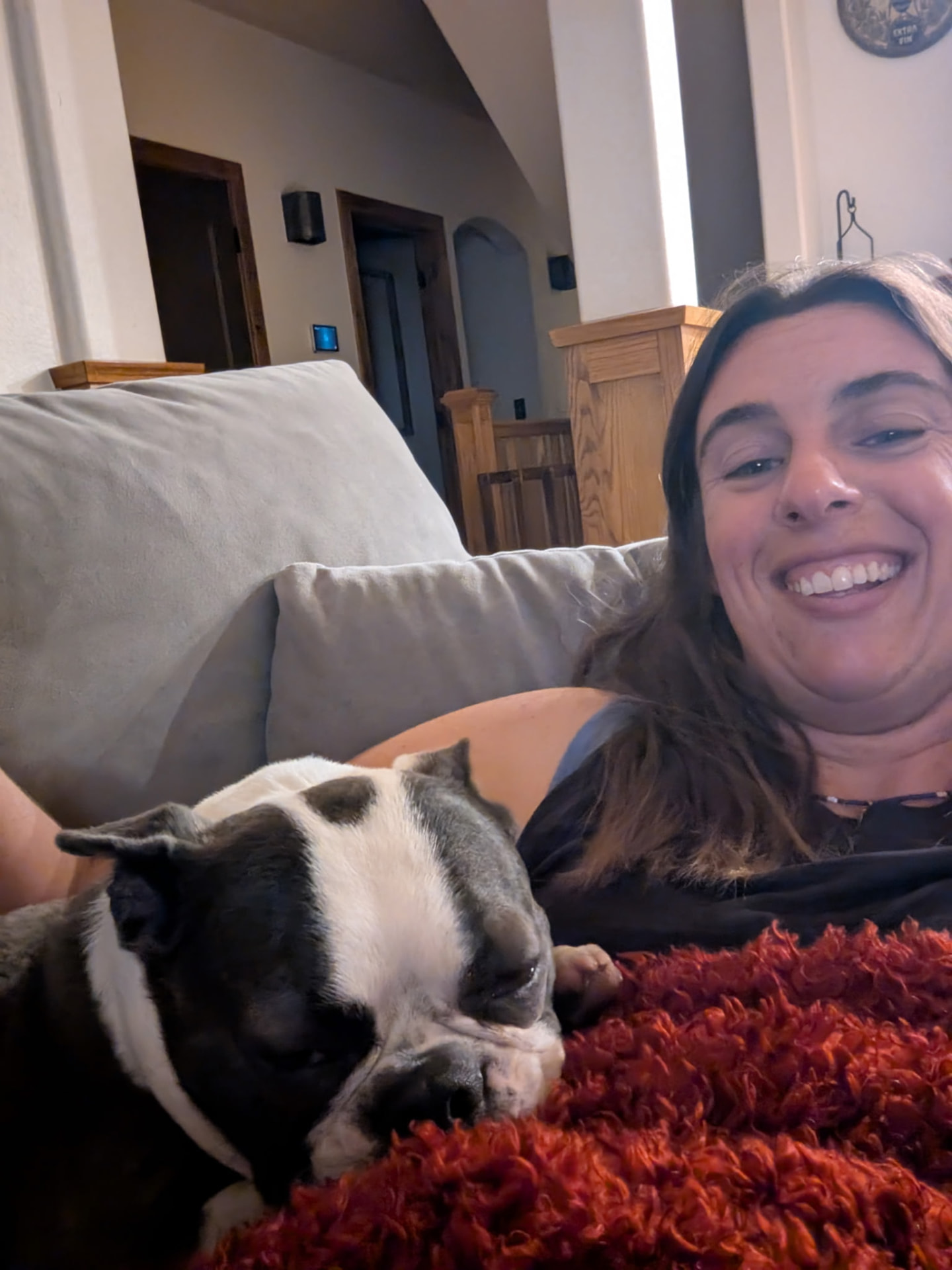 Sarah with a sleepy Boston Terrier curled up on the couch